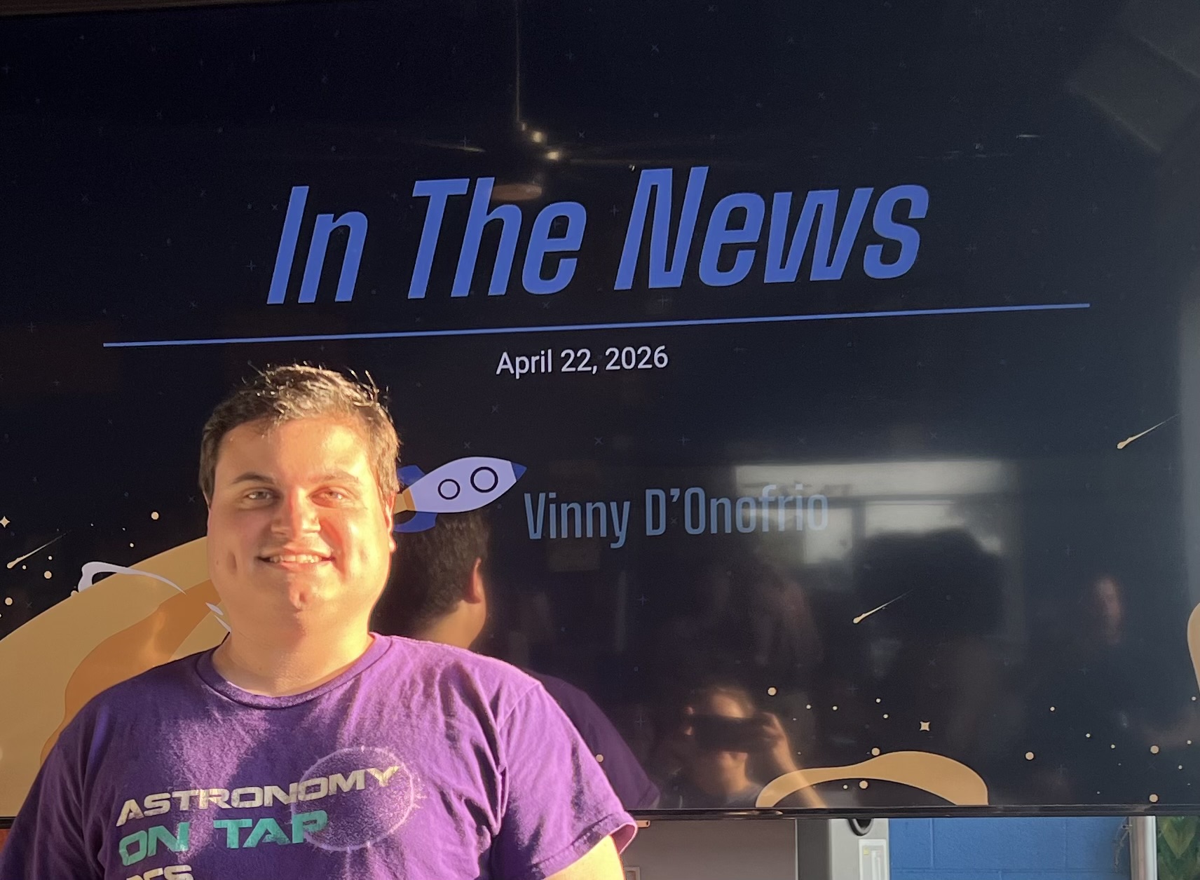 Vinny standing in front of the Astronomy on Tap In the News screen.